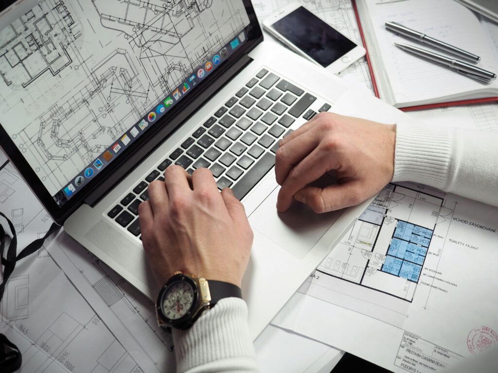 Architektas dirba su brėžiniais kompiuteryje ir popieriuje, planuodamas pastato projektą